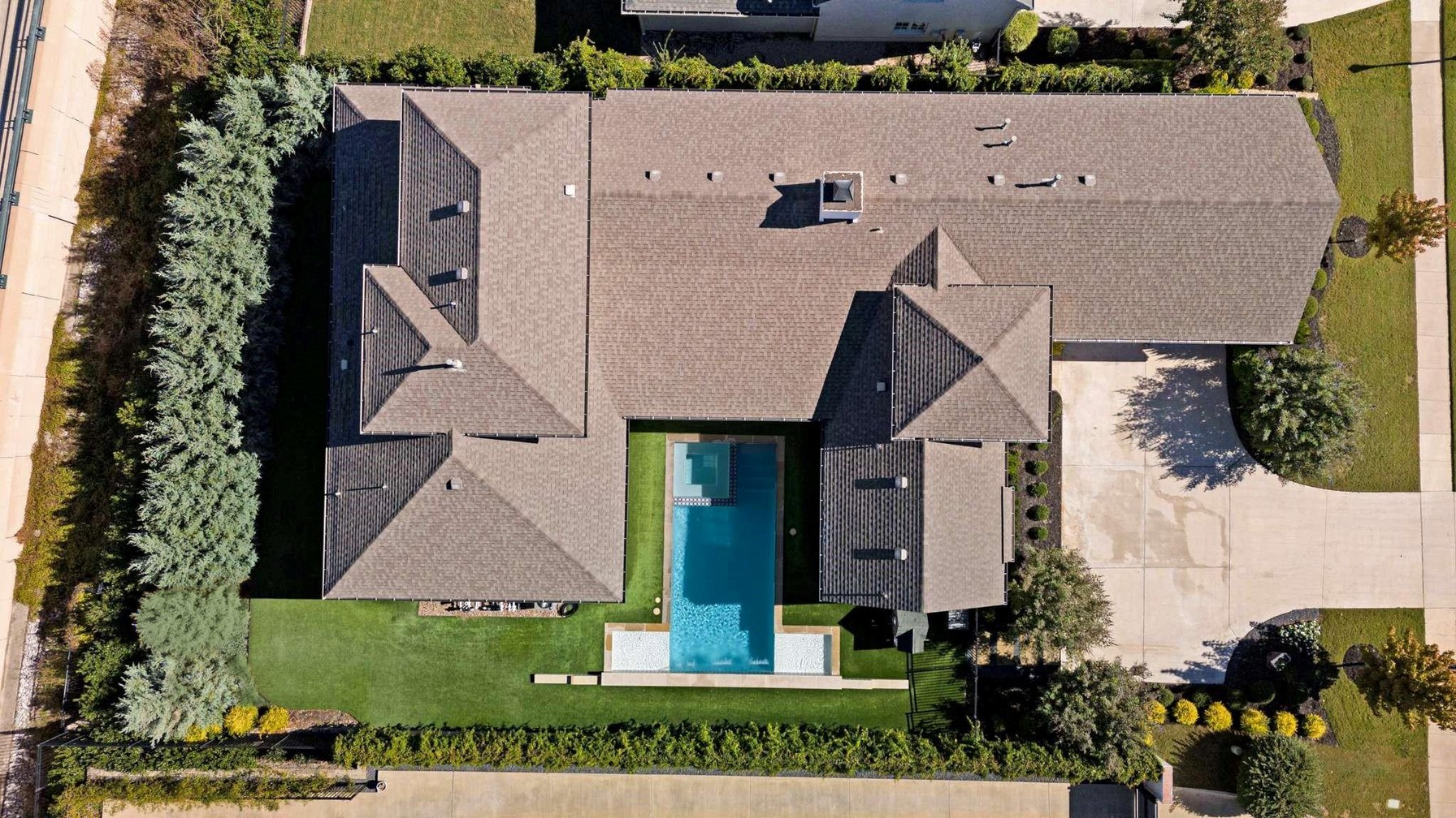 Overhead aerial of a large Fort Worth house with a pool in a central courtyard, showing one continuous roofline with no separate structure visible in the yard.